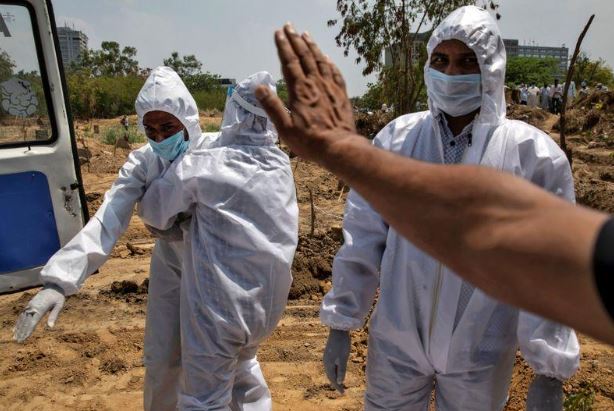 أحد الأشخاص يواسي قريب له بعد وفاة والده بسبب فيروس كورونا وذلك أثناء مراسم الدفن في نيودلهي. تصوير: دانيش صديقي-رويترز.